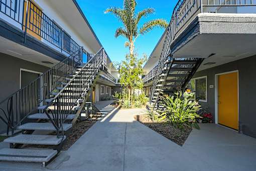 A sunny day in a courtyard surrounded by buildings with staircases.