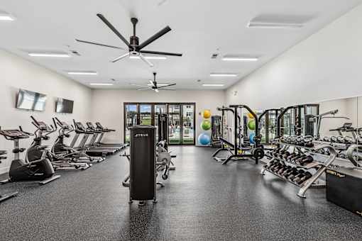 A spacious gym with a variety of equipment including treadmills, stationary bikes, and weight machines.