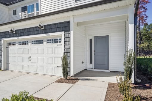 the front of a white house with a garage door