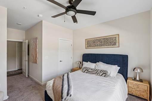 A bedroom with a large bed and a ceiling fan.