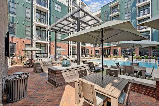 A pool area with a table and chairs and umbrellas.