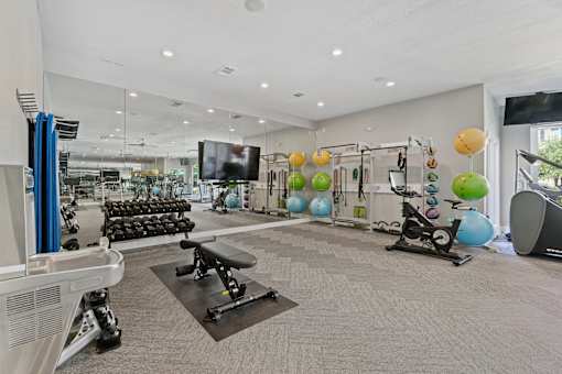 A gym with a variety of equipment including treadmills, weights, and exercise balls.