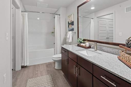 A bathroom with a toilet, sink, and mirror.
