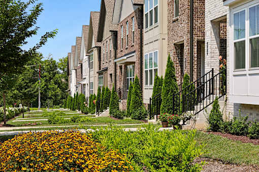 A row of townhouses with a flower bed in the foreground.