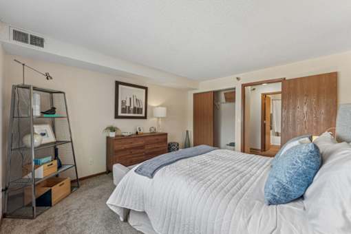 A bedroom with a large bed and a wooden dresser.
