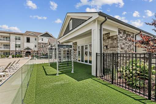 A modern house with a glass wall and a green lawn in front.
