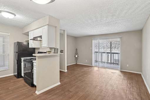A kitchen area with a black fridge and white cabinets.