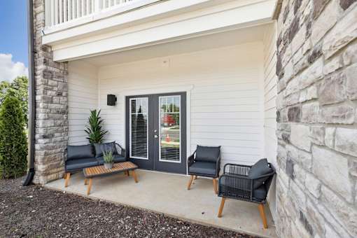 An apartment patio with a black sofa and a black chair on the porch.