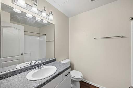 A bathroom with a sink, toilet, and mirror.
