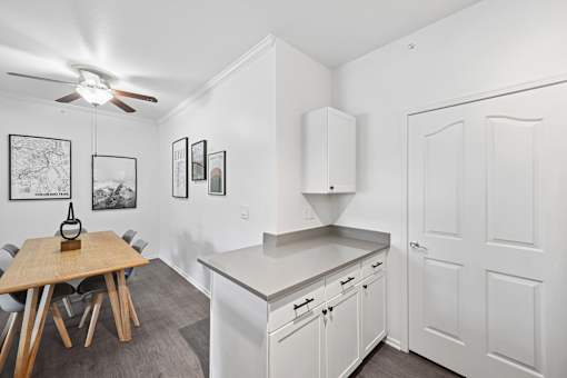 A kitchen with white cabinets and a wooden table.