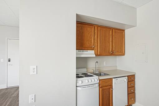 A kitchen with white appliances and wooden cabinets.