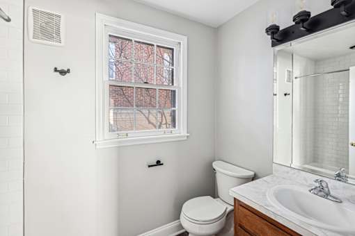 A white bathroom with a toilet, sink, and window.