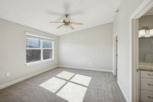 A room with a ceiling fan and a window with blinds.
