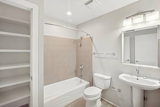 A white bathroom with a toilet, sink, and bathtub.