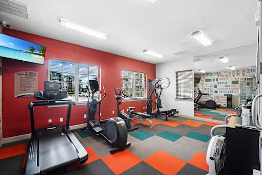 A gym with a treadmill, elliptical trainer, and other exercise equipment.