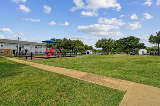 A playground with a slide and a building in the background.