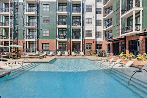 A large swimming pool in front of apartment buildings.