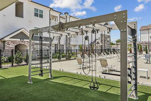 A gym set up on a grassy area in front of apartment buildings.