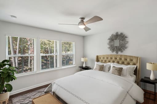 a bedroom with white walls and a ceiling fan
