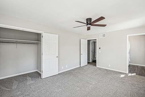 A room with a ceiling fan and a white door.