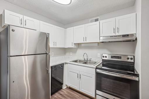 A kitchen with a stainless steel refrigerator, oven, and cabinets.