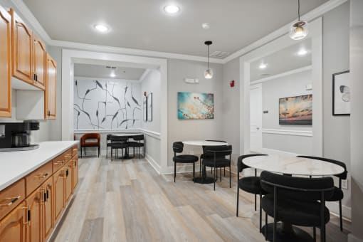 a dining room with a round table and chairs and a kitchen with a sink