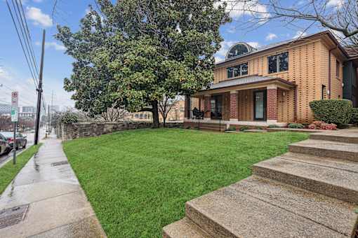 A house with a green lawn and a tree in front.