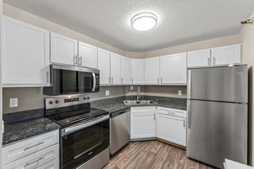 A kitchen with stainless steel appliances and white cabinets.