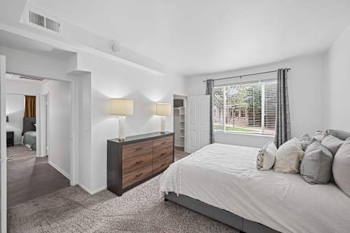 A bedroom with a bed, nightstand, and window.