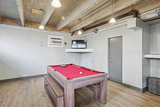 A pool table in a room with a concrete ceiling and wooden flooring.