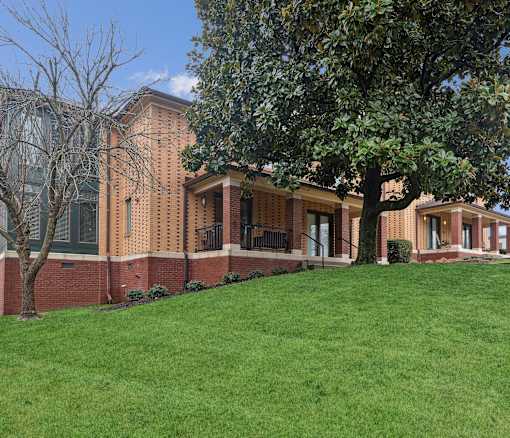 A large building with a red brick wall and a green lawn in front.