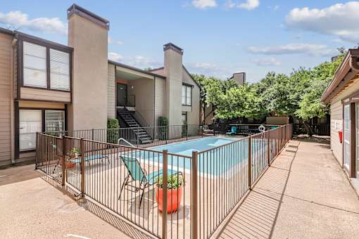 A pool surrounded by a fence with a chair and a potted plant.