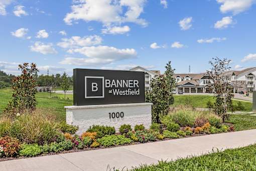 A sign for Banner at Westfield 1000 with a residential area in the background.
