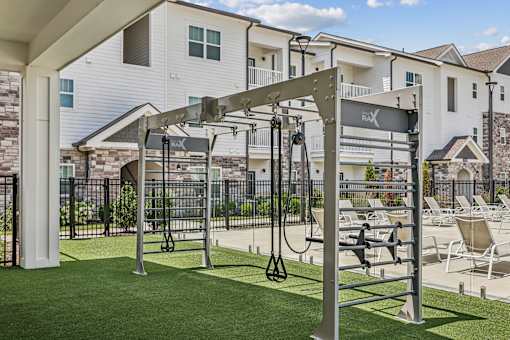 A gym with a pull up bar and a bench outside a building.