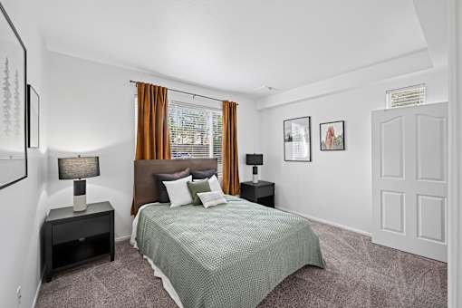 A bedroom with a bed, nightstands, and pictures on the wall.