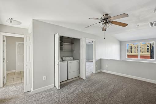 A room with a ceiling fan and a washer and dryer in it.