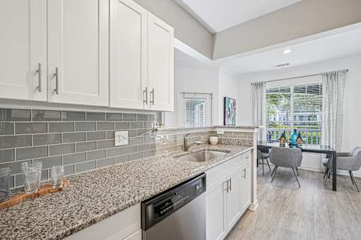 A kitchen with a granite countertop and a dining table with chairs.