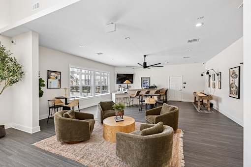 A clubroom room with a rug, chairs, and a table.