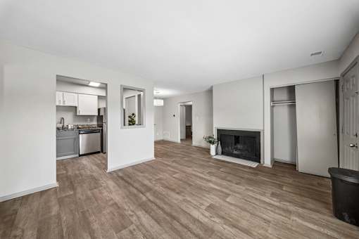 A spacious living room with a fireplace and a kitchen area in the background.