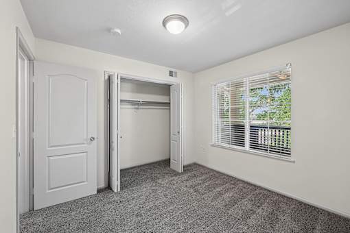 A room with a carpeted floor and a window with blinds.