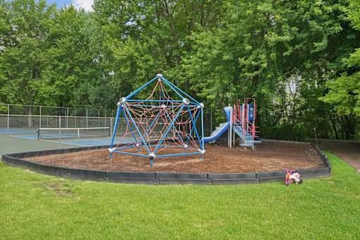 A playground with a blue and red swing set and a blue pyramid-shaped structure.