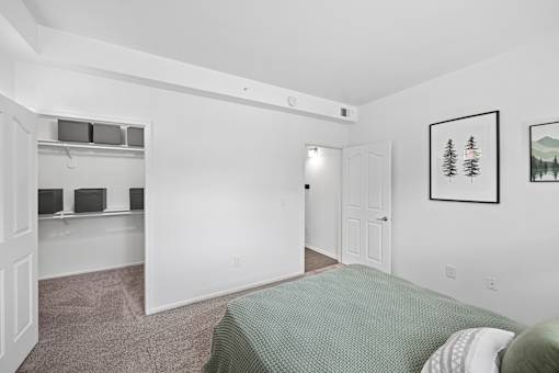 A bedroom with a bed, a shelf with speakers, and pictures on the wall.