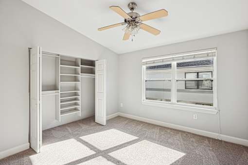 A room with a window, a fan, and a rug.