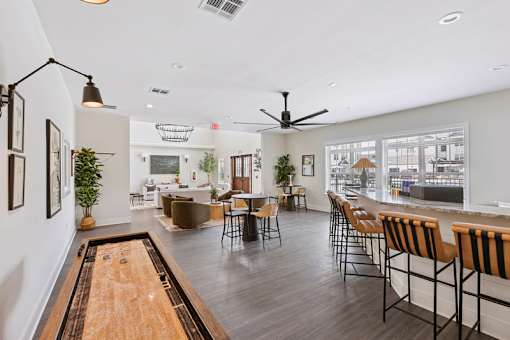 A clubroom with a shaggy rug and a long table with chairs with shuffleboard..