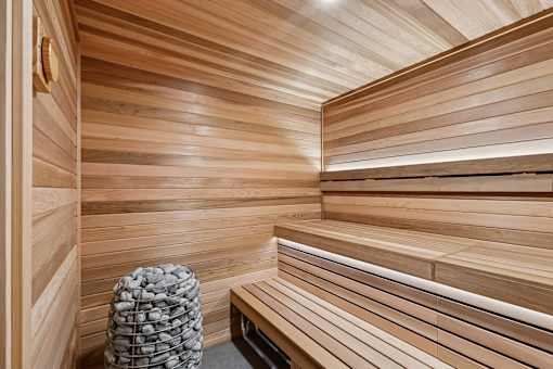 A wooden sauna with benches and a stone bucket.