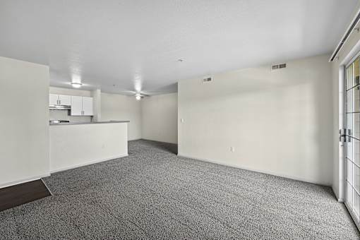 A large, empty room with a carpeted floor and white walls.
