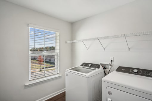 a white laundry room with a window and a white washer and dryer