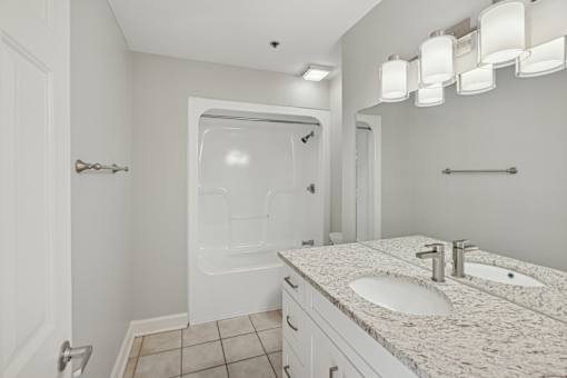 A white bathroom with a walk-in shower and double sinks.