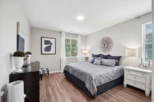 A bedroom with a bed, nightstand, and a wall clock.