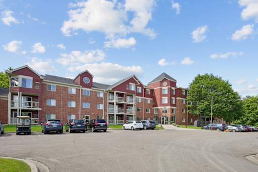 A large red brick building with a parking lot in front.
